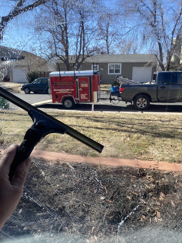 A window cleaning using a squeegee with our WGE trailer in the back ground